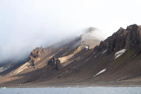 A mountain range is in the background of a body of water Stock Photos