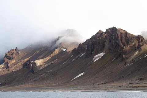 A mountain range is in the background of a body of water Stock Photos
