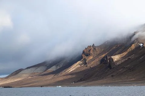 A mountain range is in the background of a body of water Stock Photos