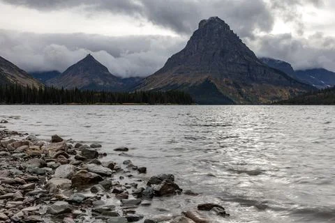 A mountain range is in the background with a lake in front of it Stock Photos