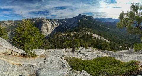 A mountain range with a clear blue sky and a few trees Stock Photos