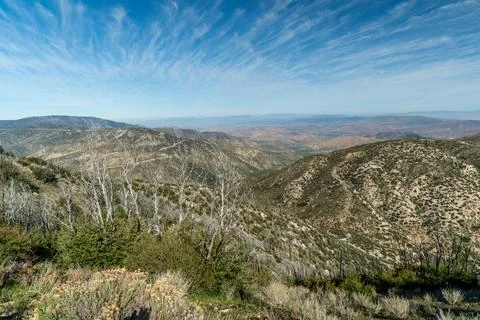 A mountain range with a clear blue sky and a few trees Stock Photos