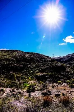A mountain range with a clear blue sky and a bright sun shining on it Stock Photos
