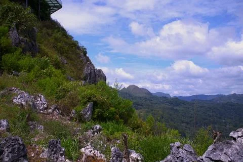 A mountain range with a cloudy sky and a lush green hillside Stock Photos