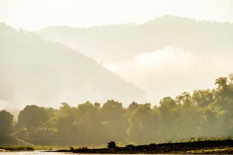 A mountain range with a cloudy sky and a river in the foreground Stock Photos