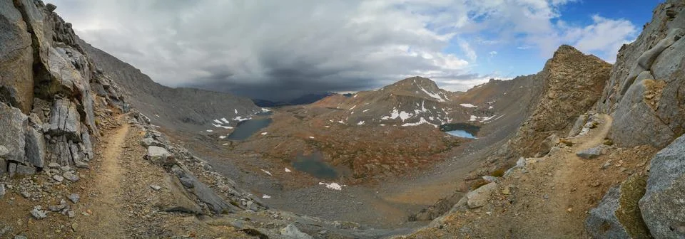 A mountain range with a cloudy sky and snow on the ground Stock Photos
