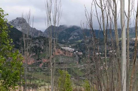 A mountain range with a cloudy sky and a few trees Stock Photos