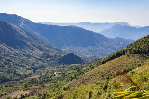 Mountain range covered with dense green forests and bright blue sky at mornin 写真素材