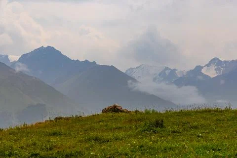 Mountain Range with Green Meadow and Hazy Sky Stock Photos