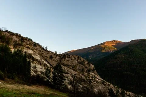 A mountain range illuminated by warm sunlight during the early sunset (French Stock Photos