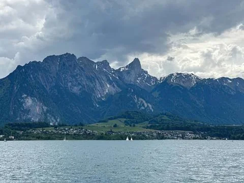 Mountain range with lake and cloudy sky in the background Stock Photos