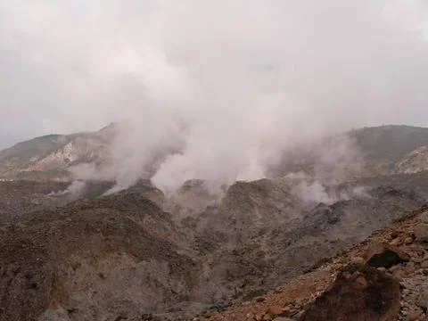 A mountain range with a large cloud of smoke rising from the top Stock Photos