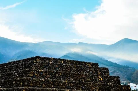 A mountain range with a large stone structure in the middle Stock Photos