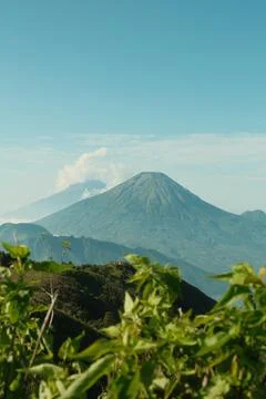 A mountain range with a large volcano in the background Stock Photos