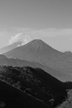 A mountain range with a large volcano in the middle Stock Photos
