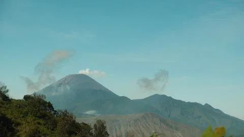 A mountain range with a large volcano in the middle Stock Photos