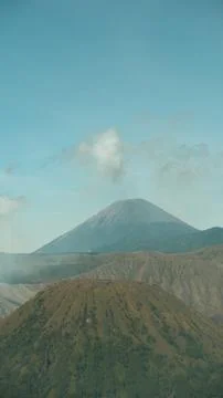 A mountain range with a large volcano in the middle Stock Photos