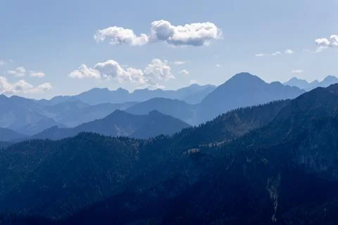 Mountain range layers with forest peaks under blue sky Stock Photos
