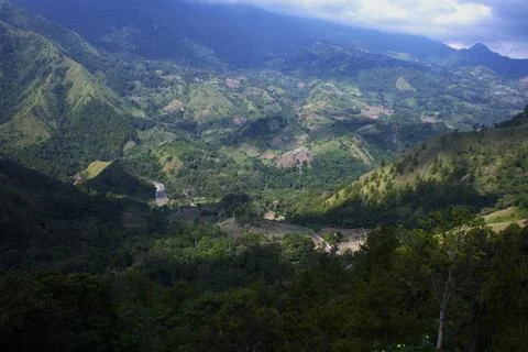 A mountain range with a lush green forest and a river running through it Stock Photos