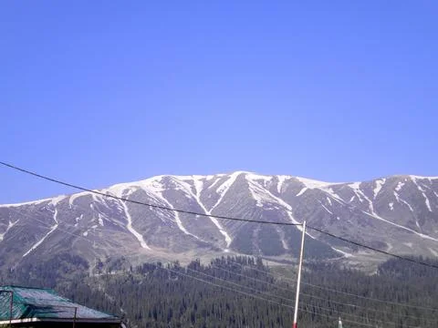 Mountain range with partial snow coverage against a clear blue sky Stock-Fotos