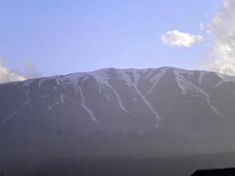 Mountain range with partial snow coverage against a clear blue sky Photos