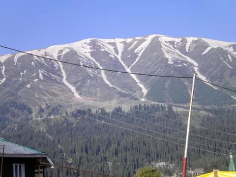 Mountain range with partial snow coverage against a clear blue sky Stock Photos