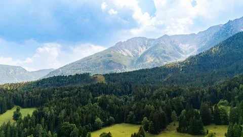 A mountain range rises above dense woodland and exposed slopes.. Gray ridge.. Stock Photos