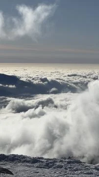 Mountain range rising above clouds under dramatic sky Stock Photos