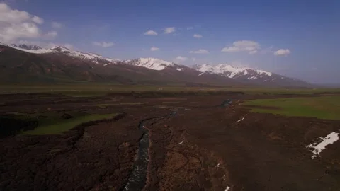 Mountain range with a river and green field. Aerial view. The sky is clear and Stock Footage 274051345