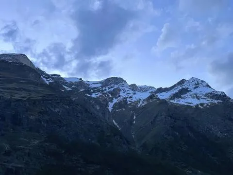 Mountain range with snow and cloudy sky in the background Stock Photos