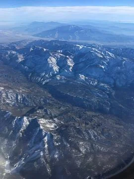 Mountain range with snow caps seen from airplane window Stock Photos