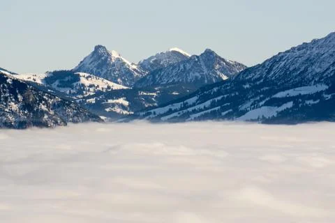 Mountain range with snow in low lying valley fog with silhouettes. Scenic snowy Stock Photos