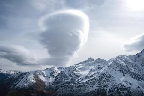 Mountain range, steep snow-covered rocky slopes, peaks and large bizarre clou Stock Photos