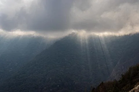 Mountain range with sun ray beams and heavy cloud overcast at day 스톡 사진