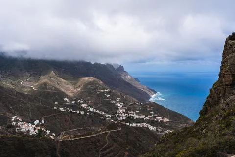 A mountain range with a town in the valley and a body of water in the distance 写真素材