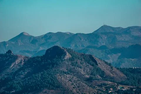 A mountain range with trees on its slopes under a blue sky Stock Photos