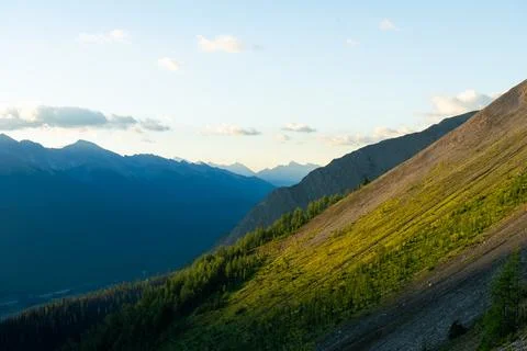 A mountain range view with sunlit peaks and valleys under a blue sky. Stock Photos