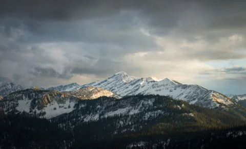 A mountain range viewed in fall as the sun illuminates the peak during sunset Stock Photos