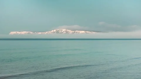 A mountain range is visible in the distance behind a body of water Stock Footage 303987780