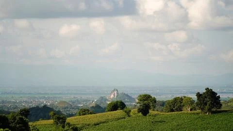 A mountain range is visible in the distance, with a small hill in the foreground Stock Photos