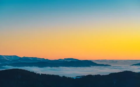 Mountain range with visible silhouettes through the morning colorful fog.Tarc Stock Photos