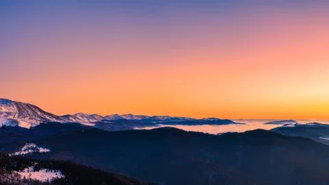 Mountain range with visible silhouettes through the morning colorful fog.Tarc Stock Photos