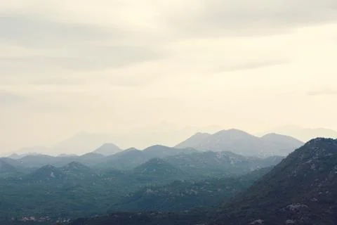 Mountain range with visible silhouettes through the morning colorful fog Stock Photos