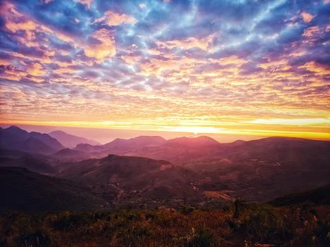 Mountain range with visible silhouettes through the morning colorful fog. Stock Photos