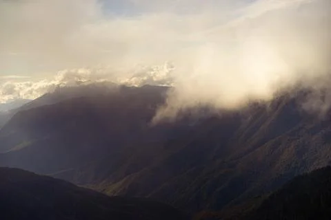 Mountain range with visible silhouettes through the morning colorful fog. Stock Photos
