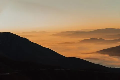 Mountain range with visible silhouettes through the morning colorful fog Foto stock