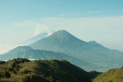 A mountain range with a volcano in the background Stock Photos