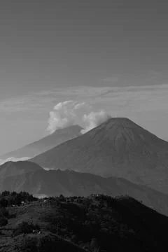 A mountain range with a volcano in the middle Stockfoto's