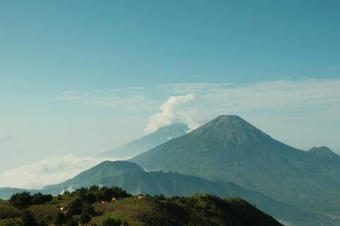 A mountain range with a volcano in the middle Stock Photos