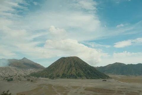 A mountain range with a volcano in the middle Stock Photos